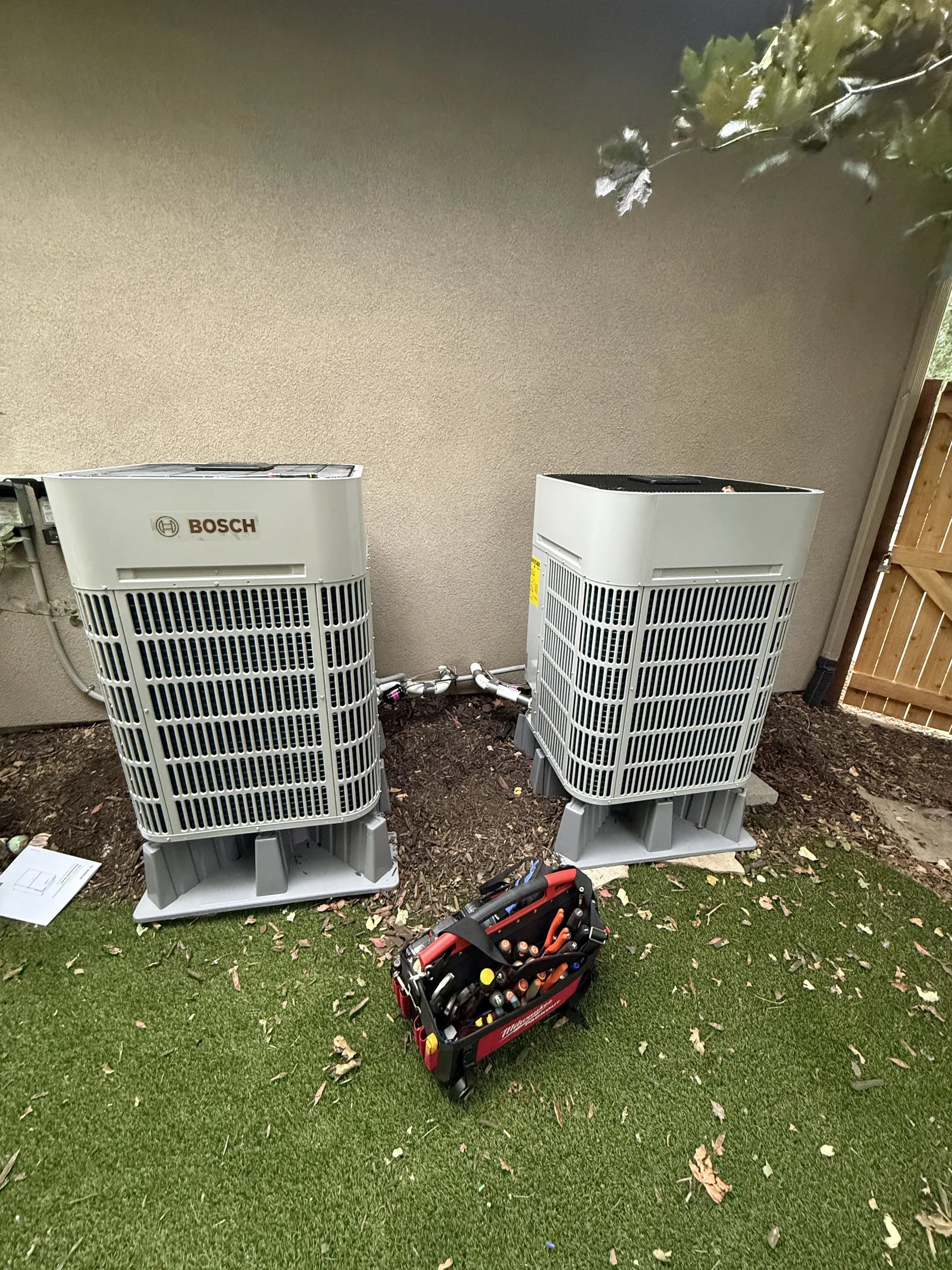 Two Bosch outdoor units on risers against a stucco wall